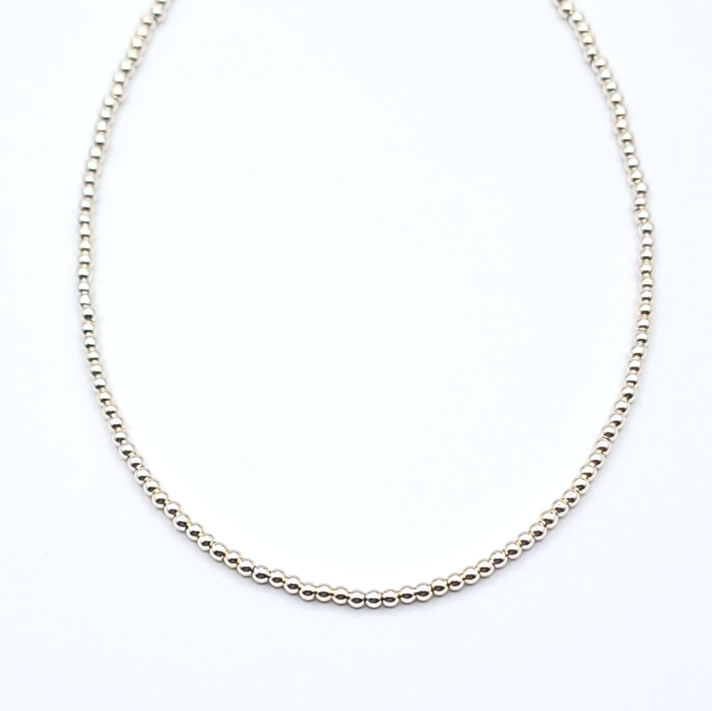 Close-up of gold filled beaded choker necklace showing minimalist chain detail on white background
