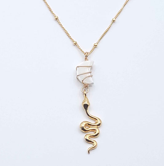 Gold-filled Snake Charmer necklace featuring a mother of pearl crescent moon and gold serpent pendant on a soft light gray background