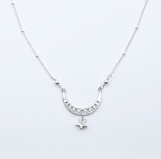Sterling silver crescent moon necklace with star charm pendant in celestial minimalist style on white background