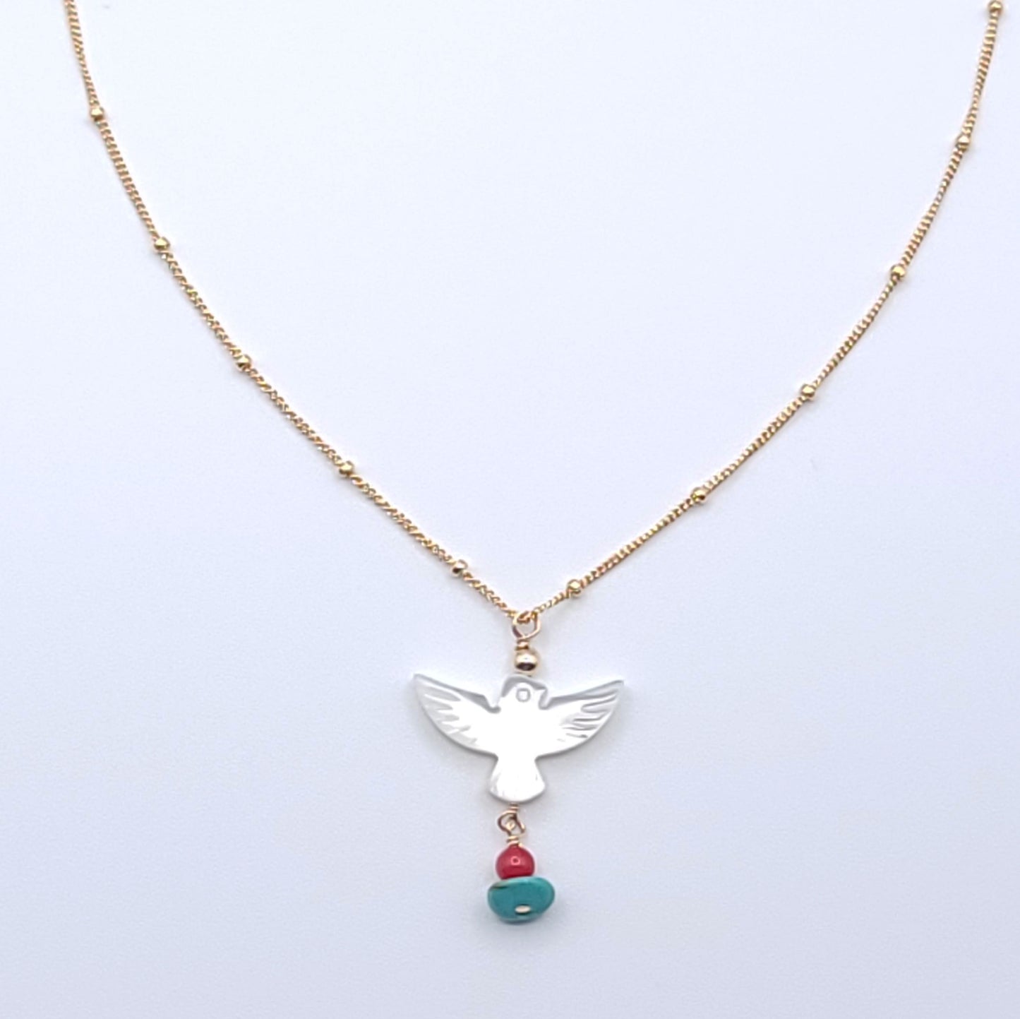 Wings of Hope Necklace featuring a mother-of-pearl bird pendant accented with turquoise and coral on an 16-inch gold-filled satellite chain.