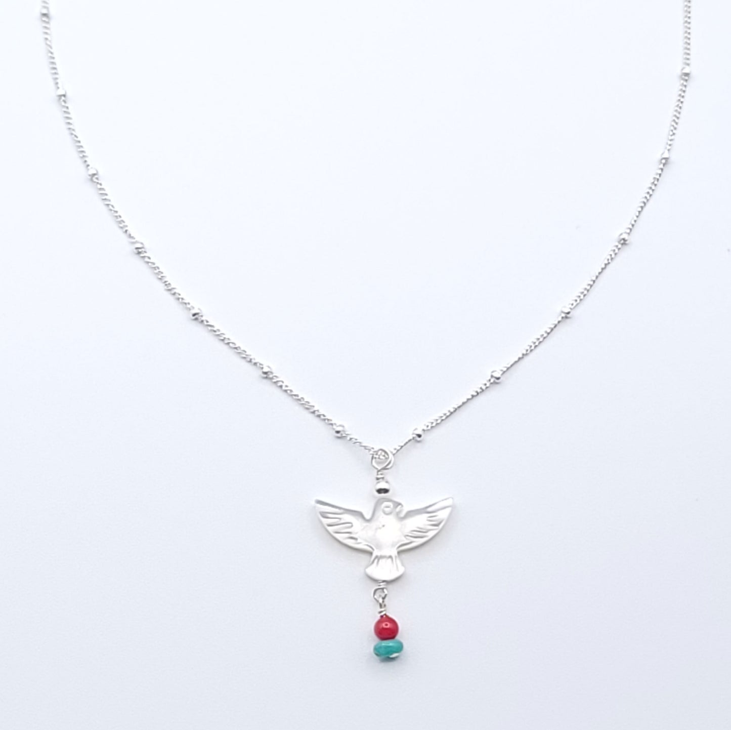 Wings of Hope Necklace featuring a mother-of-pearl bird pendant accented with turquoise and coral on an 16-inch sterling silver satellite chain.