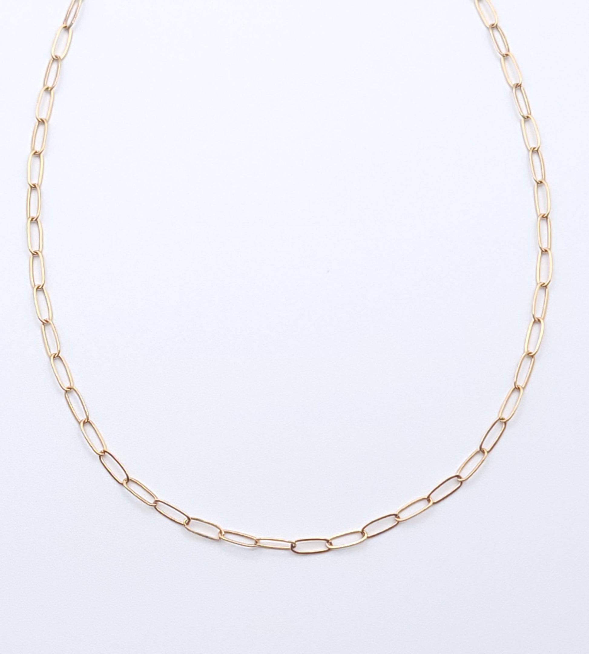 Minimal gold-filled essential chain necklace on a soft light gray background.