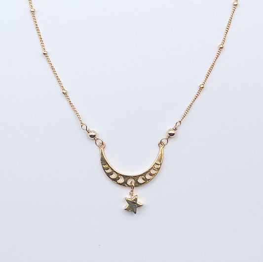 Gold crescent moon necklace with star charm pendant in celestial minimalist style on light background