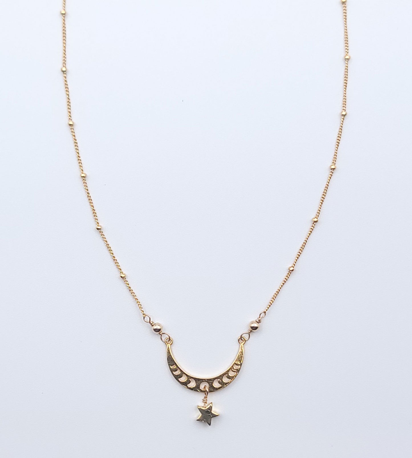 Gold crescent moon necklace with star charm pendant, full view in celestial minimalist style on light background