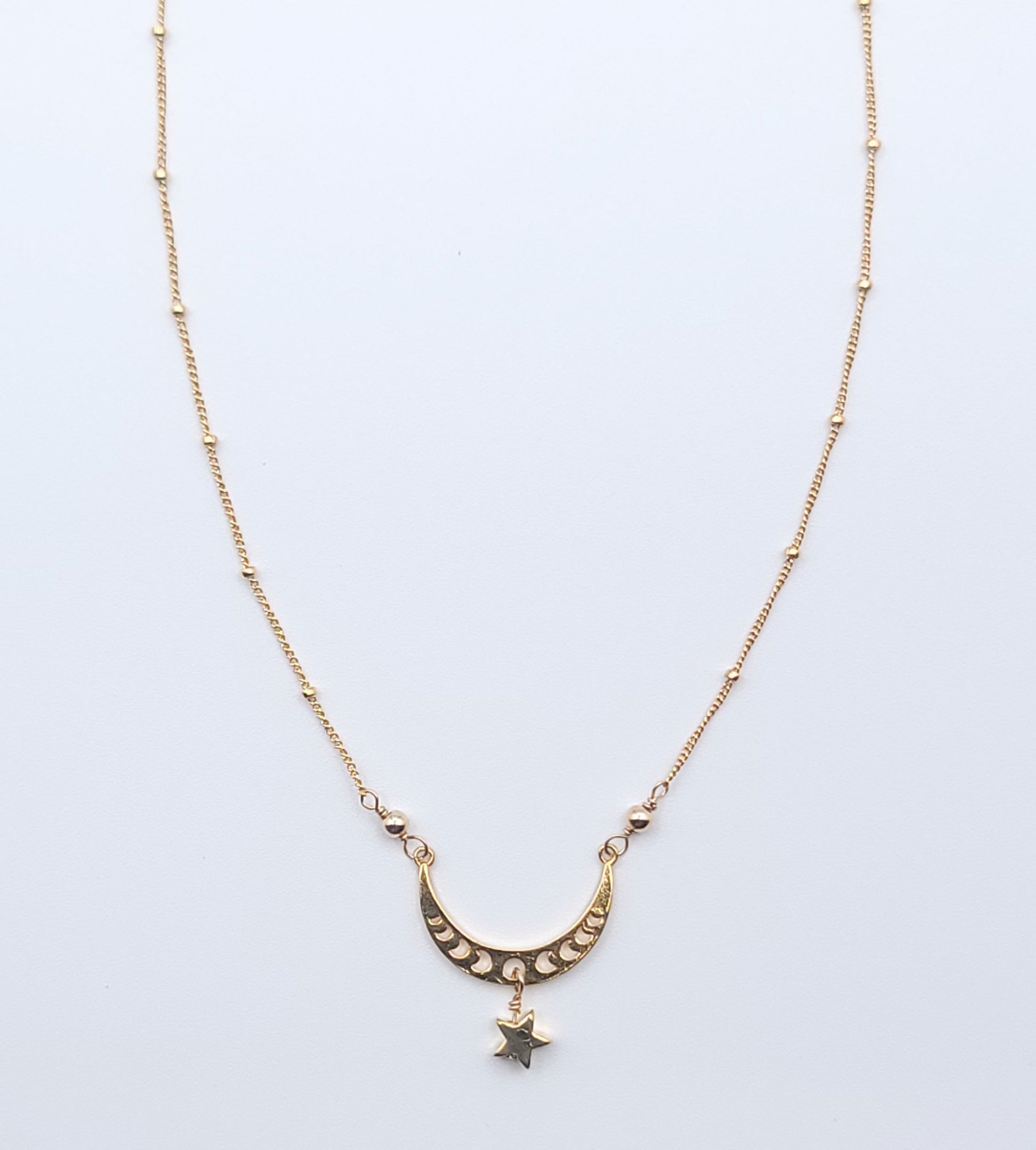 Gold crescent moon necklace with star charm pendant, full view in celestial minimalist style on light background