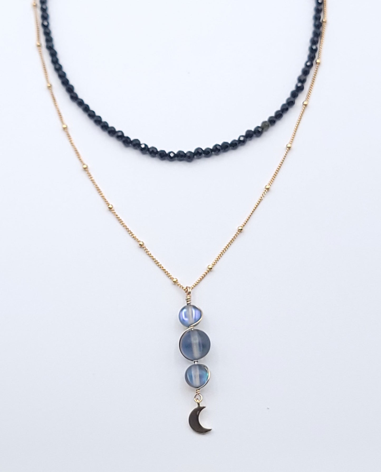 Layered gold-filled midnight necklace stack featuring the Moon Phases Silver Aura necklace and Boundless Protection choker on a soft light gray background