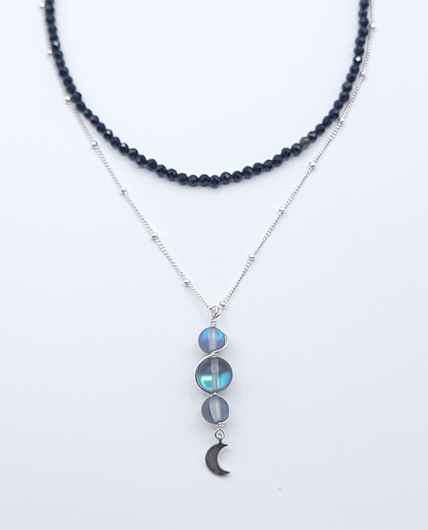 Layered sterling silver midnight necklace stack featuring the Moon Phases Silver Aura necklace and Boundless Protection choker on a soft light gray background