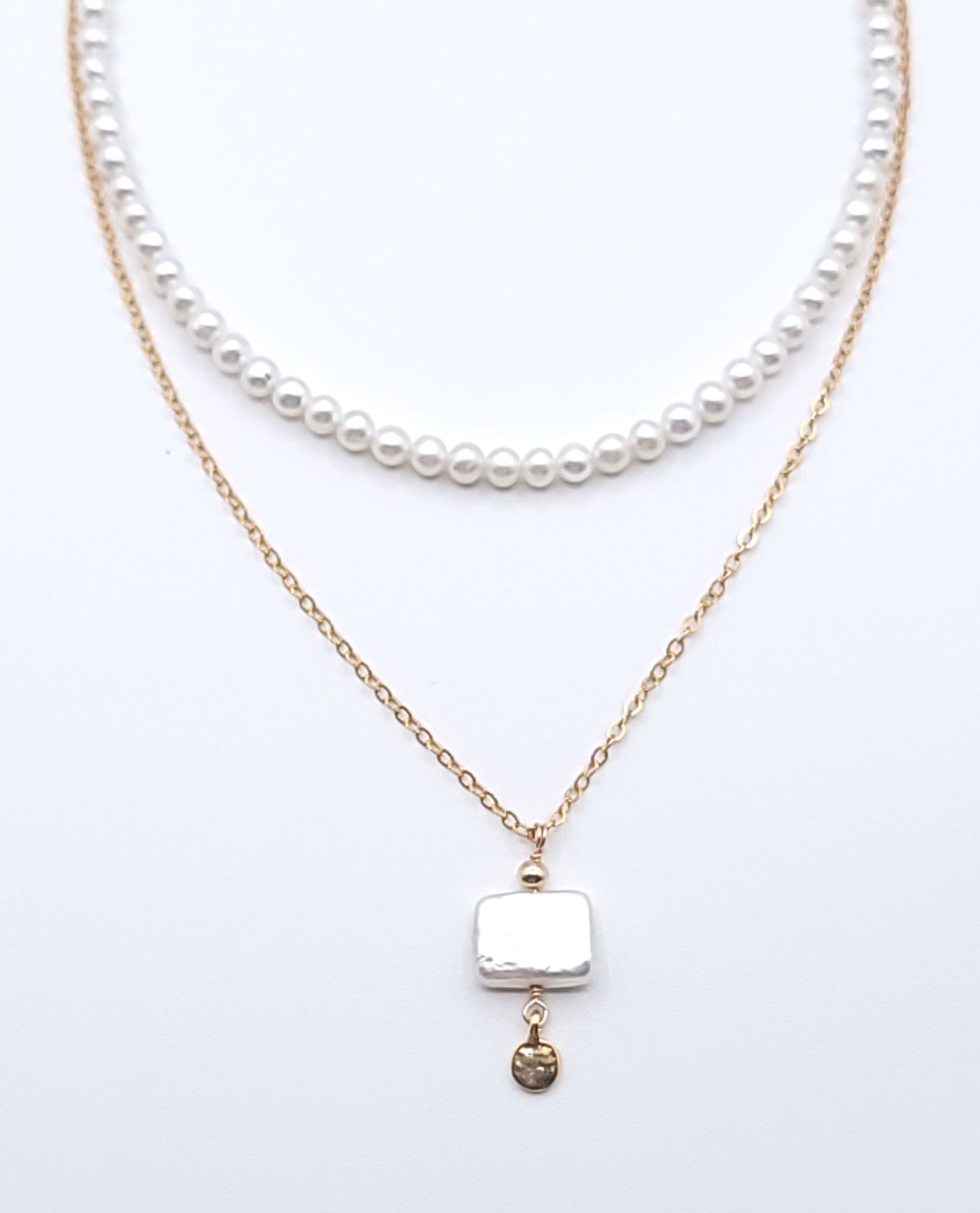 Layered gold-filled pearl necklace stack featuring the Quiet Light pendant necklace with mother of pearl on a soft light gray background