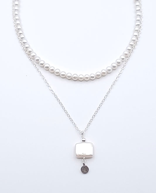 Layered sterling silver pearl necklace stack featuring the Quiet Light pendant necklace with mother of pearl on a soft light gray background
