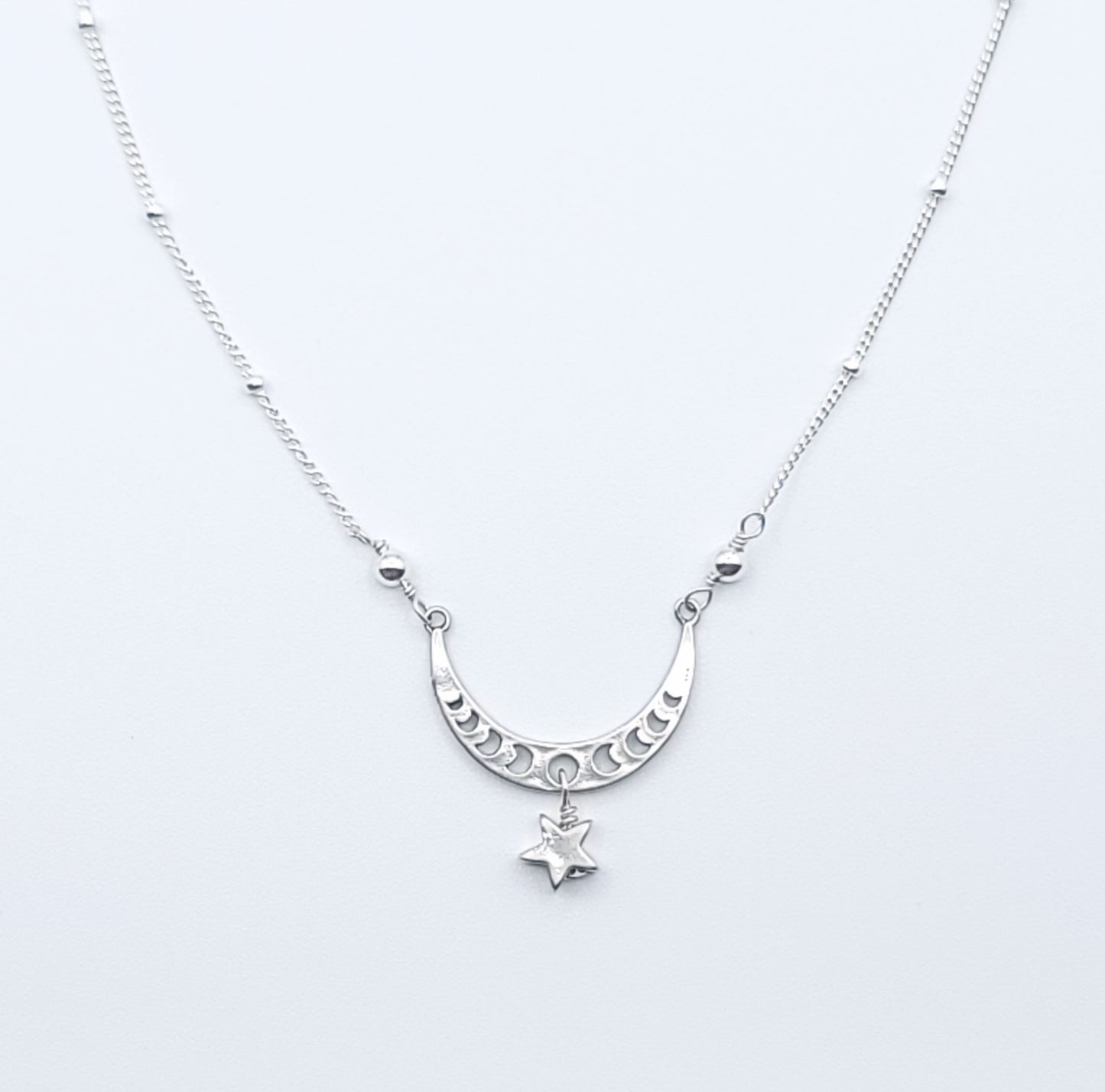 Sterling silver crescent moon necklace with star charm pendant in celestial minimalist style on white background