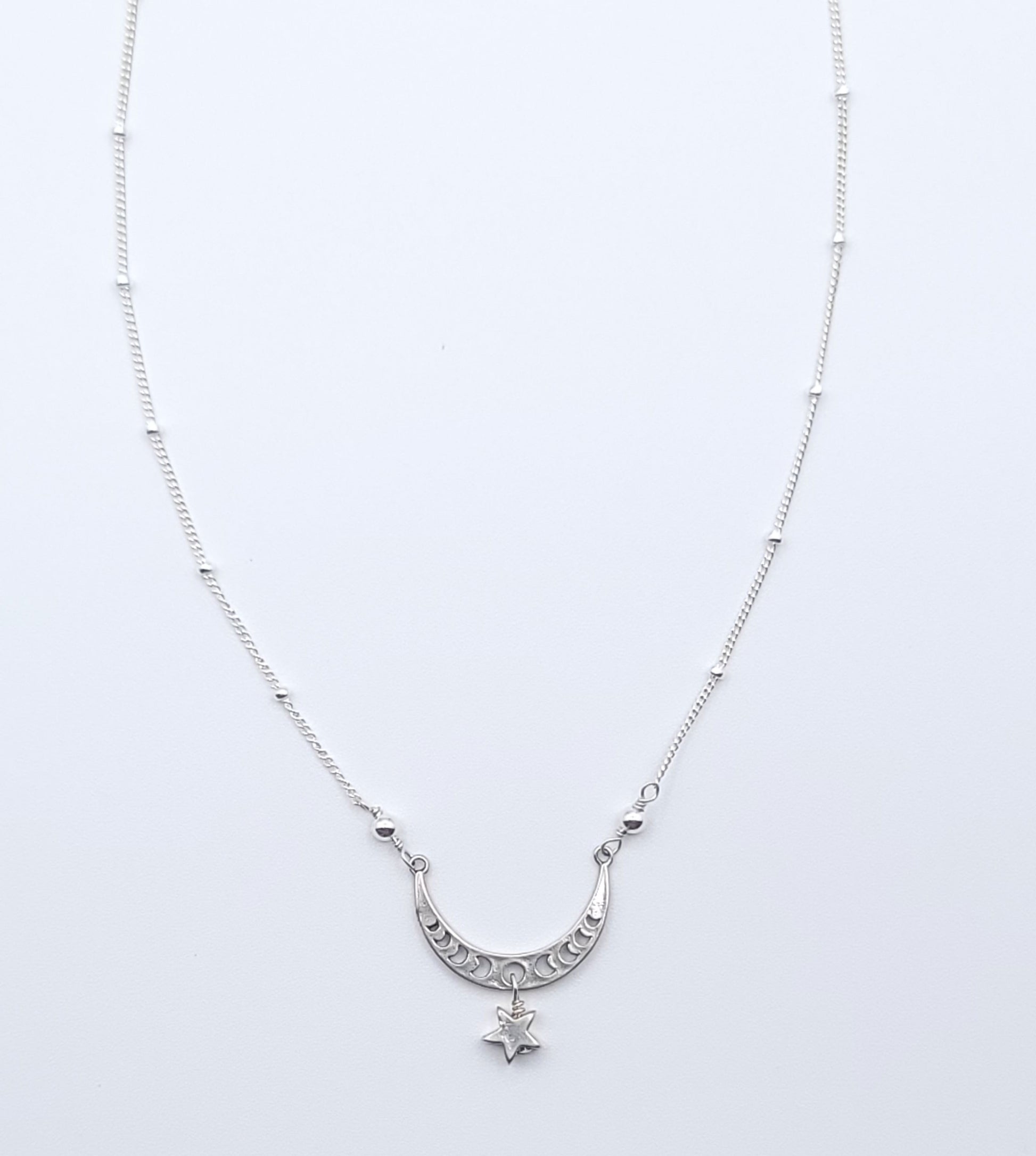 Sterling silver crescent moon necklace with star charm pendant, full view in celestial minimalist style on light background