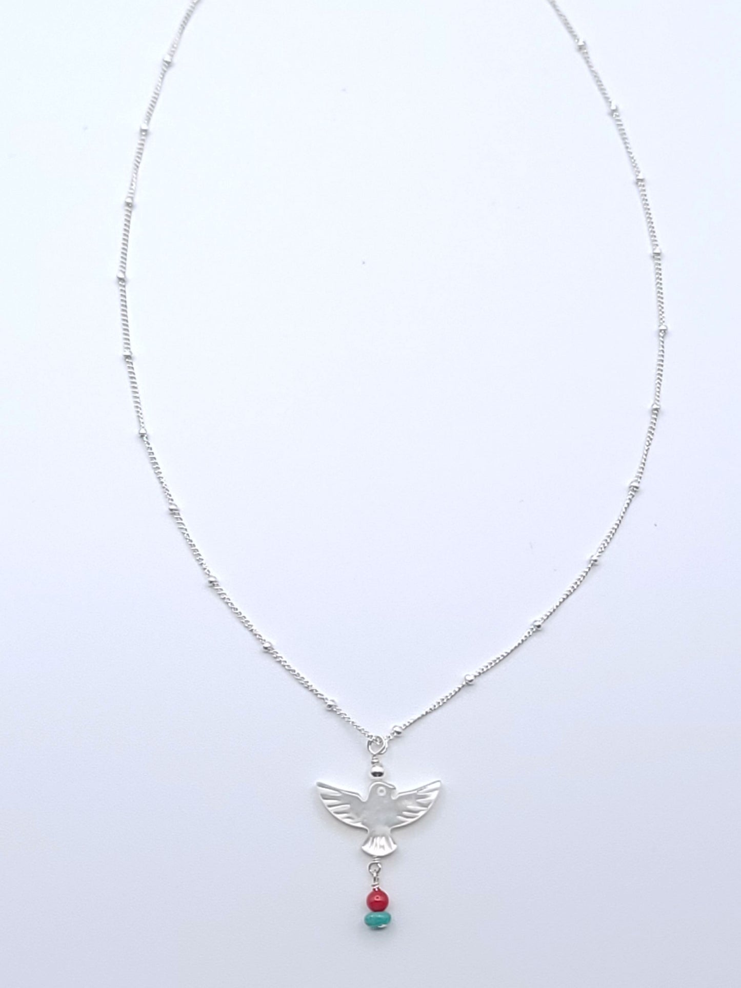Wings of Hope Necklace featuring a mother-of-pearl bird pendant accented with turquoise and coral on an 16-inch sterling silver satellite chain.