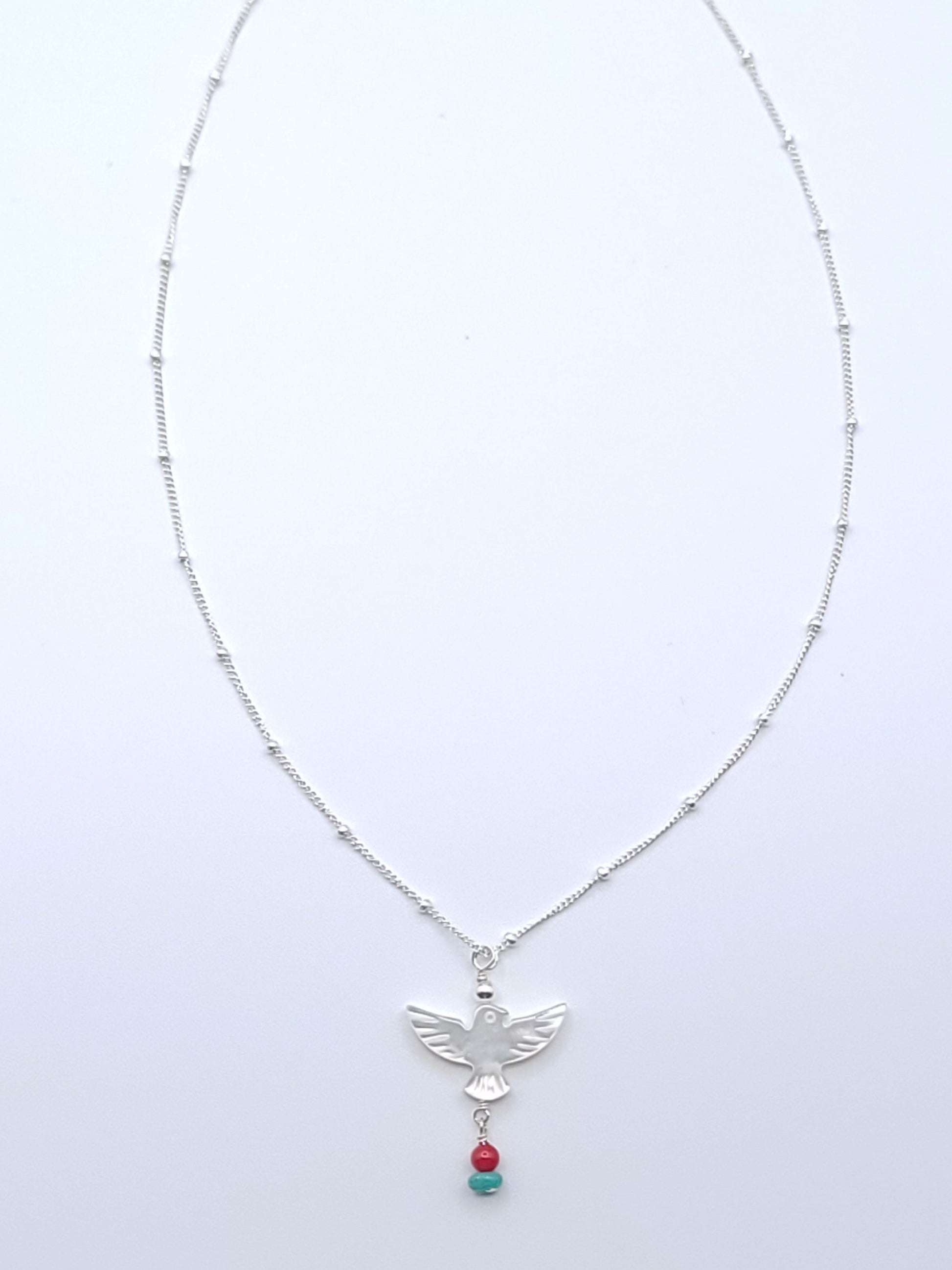 Wings of Hope Necklace featuring a mother-of-pearl bird pendant accented with turquoise and coral on an 16-inch sterling silver satellite chain.